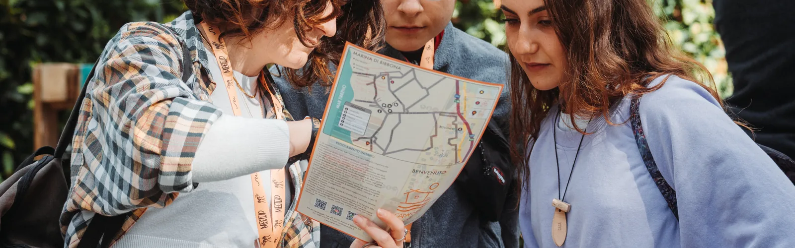 Tre partecipanti chine sulla mappa di carta del festival: nessuno schermo in mano